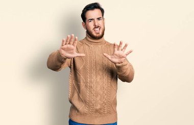 Günlük giysiler giyen genç İspanyol adam korku ifadesinden korkuyor ve dehşete düşüyor. El hareketlerini durdur, şok içinde bağır. panik konsepti. 