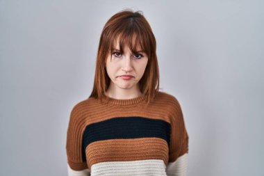 İzole edilmiş arka planda çizgili süveter giyen genç ve güzel bir kadın üzgün ve endişeli, sinirli ve korkmuş bir şekilde ağlıyor. hüzünlü ifade. 