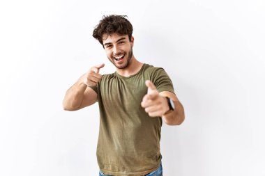 Hispanic man standing over isolated white background pointing fingers to camera with happy and funny face. good energy and vibes. 