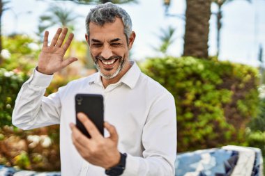 Şehirdeki akıllı telefondan video görüşmesi yapan orta yaşlı, kır saçlı bir adam..