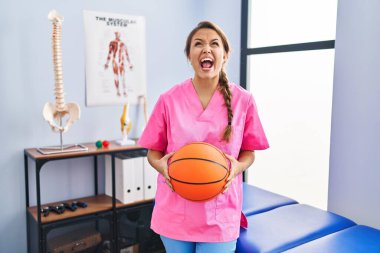 Fizyoterapi kliniğinde çalışan genç İspanyol kadın elinde basketbol topu tutarken kızgın ve kızgın çığlıklar atıyordu. Öfkeliydi ve öfkeliydi.. 