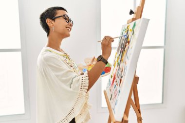 Genç İspanyol kadın resim stüdyosunda kendine güvenen gülümsüyor.