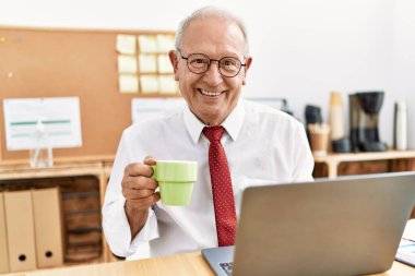 Üst düzey iş adamı kahve içiyor, ofiste çalışıyor.