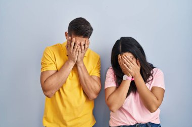 İzole edilmiş arka planda duran genç bir çift. Ağlarken yüzlerini ellerle kapatan üzgün bir ifade. depresyon kavramı. 