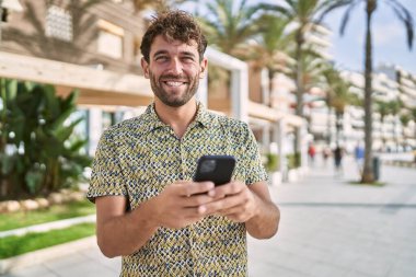 Sokakta akıllı telefon kullanan, kendine güvenen genç bir İspanyol.