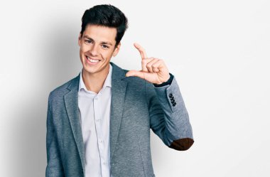 İş kıyafetleri giymiş, gülümseyen, el hareketleriyle el hareketi yapan, parmaklarıyla işaret yapan ve kameraya bakan genç İspanyol bir adam. ölçüm kavramı. 