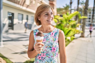 Orta yaşlı güzel bir kadın parkta dondurma tutuyor.