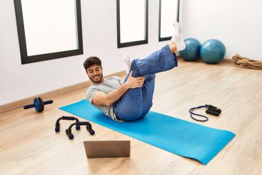 Spor salonunda online spor dersi aldığı için mutlu gülümseyen İspanyol genç adam..