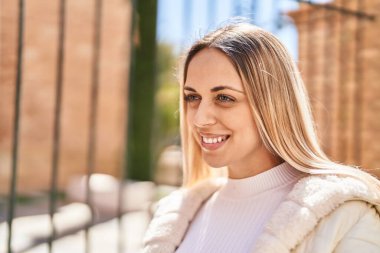 Kendine güvenen genç bir kadın caddede kollarını kavuşturmuş duruyor.