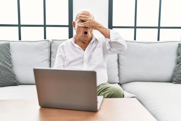 Senior Man Using Laptop Home Sitting Sofa Peeking Shock Covering — ストック写真