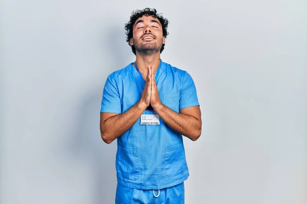 Young Hispanic Man Wearing Blue Male Nurse Uniform Begging Praying — Stockfoto