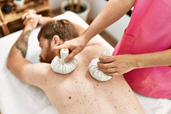 Young Redhead Man Having Back Massage Using Thai Bags Beauty — Zdjęcie stockowe