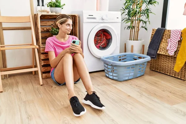 Jovem Caucasiana Usando Smartphone Esperando Máquina Lavar Roupa Lavanderia — Fotografia de Stock