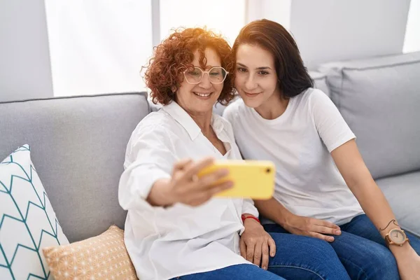 İki kadın anne ve kız evde akıllı telefondan selfie çekiyorlar.
