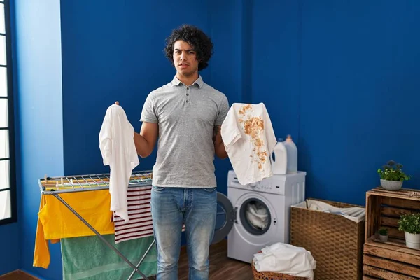 头发卷曲的西班牙裔男人拿着干净的白色T恤和肮脏的污迹 杂乱无章的T恤 怀疑概念 — 图库照片