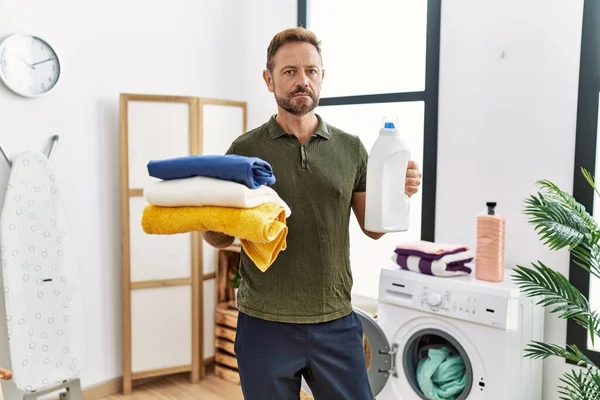 Middle Age Man Holding Clean Laundry Detergent Bottle Relaxed Serious — стоковое фото