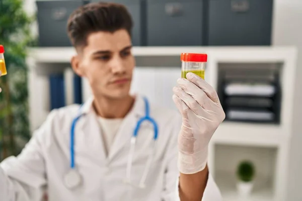 Young Hispanic Man Wearing Doctor Uniform Analysing Urine Test Tubes — Stok fotoğraf