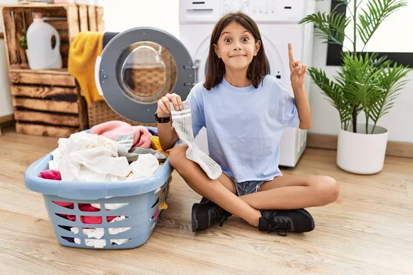 Young Hispanic Girl Doing Laundry Holding Socks Smiling Amazed Surprised — ストック写真