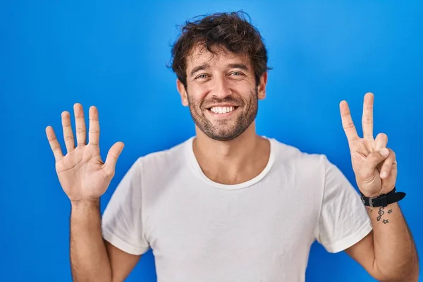 Spaanse Jongeman Staande Blauwe Achtergrond Tonen Wijzen Met Vingers Nummer — Stockfoto