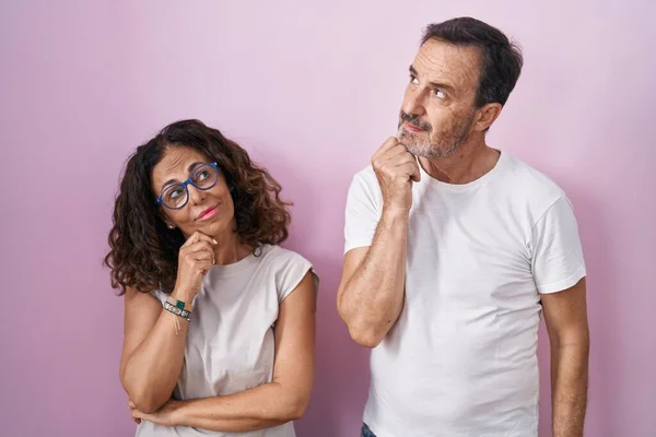 Middle Age Hispanic Couple Together Pink Background Hand Chin Thinking — ストック写真
