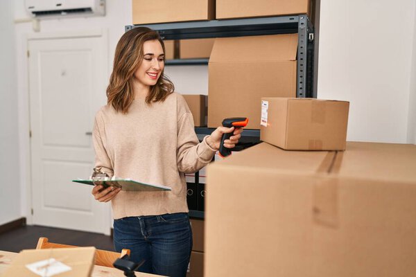 Young woman ecommerce business worker scanning package at office