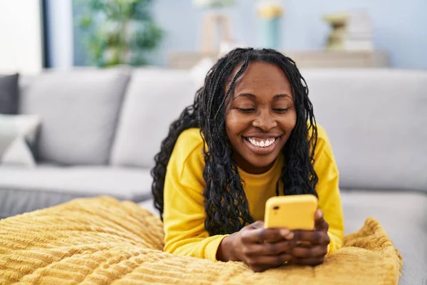 African American Woman Using Smartphone Lying Sofa Home — стоковое фото