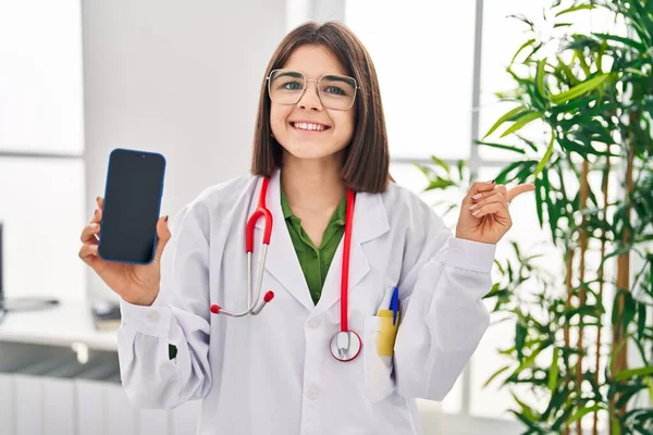 Young Hispanic Doctor Woman Showing Smartphone Screen Smiling Happy Pointing — Stock fotografie