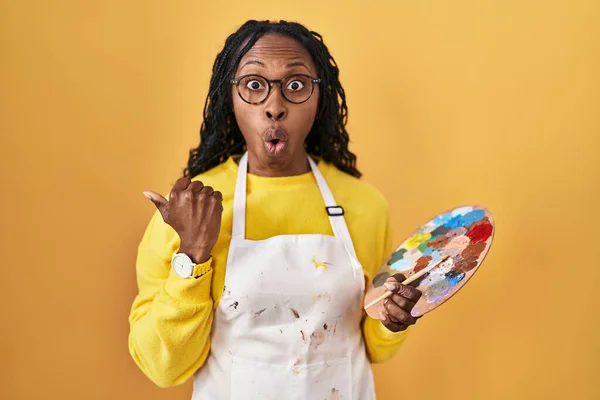 African Woman Holding Painter Palette Surprised Pointing Hand Finger Side — Stockfoto