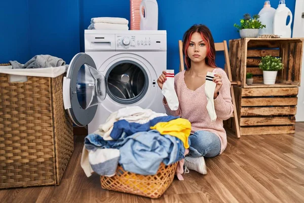 Young Caucasian Woman Doing Laundry Holding Socks Relaxed Serious Expression — ストック写真
