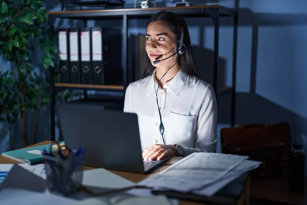 Young Brunette Woman Wearing Call Center Agent Headset Working Late — стоковое фото
