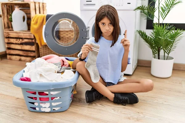 Young Hispanic Girl Doing Laundry Holding Socks Pointing Looking Sad — Foto Stock