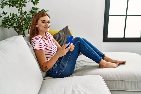 Mujer Joven Usando Teléfono Inteligente Sentado Sofá Casa —  Fotos de Stock