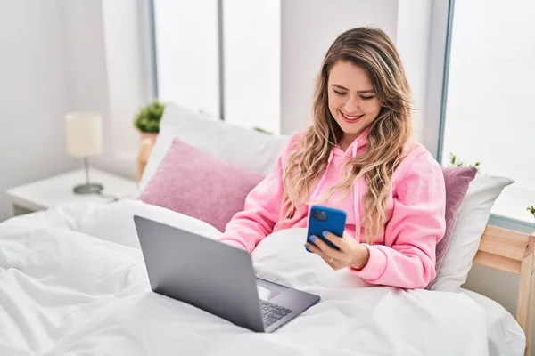 Young Woman Using Laptop Smartphone Sitting Bed Bedroom — Φωτογραφία Αρχείου