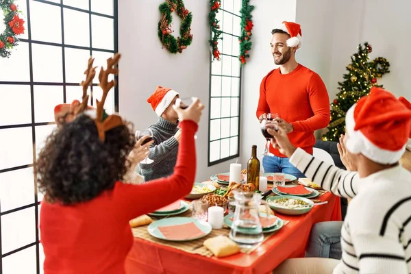 一群年轻人笑着高兴地在家里吃圣诞大餐和祝酒词 — 图库照片