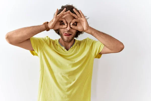 Homem Hispânico Jovem Sobre Fundo Isolado Fazendo Gesto Como Binóculos — Fotografia de Stock