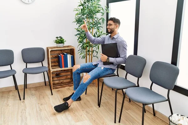 Jovem Árabe Homem Com Dedo Levantado Segurando Aglutinante Sentado Cadeira — Fotografia de Stock