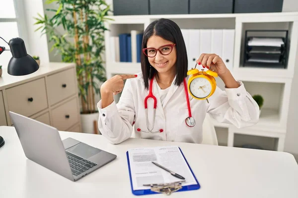 Joven Doctora Hispana Sosteniendo Despertador Clínica Señalando Con Dedo Uno — Foto de Stock