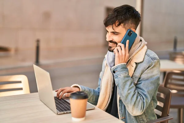 Young Hispanic Man Using Laptop Talking Smartphone Sitting Table Coffee — Stockfoto