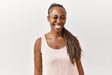 Black woman with braids standing over isolated background winking looking at the camera with sexy expression, cheerful and happy face. 