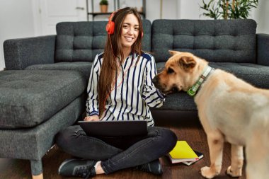 Genç İspanyol kadın dizüstü bilgisayar kullanıyor evde köpekle oturuyor.