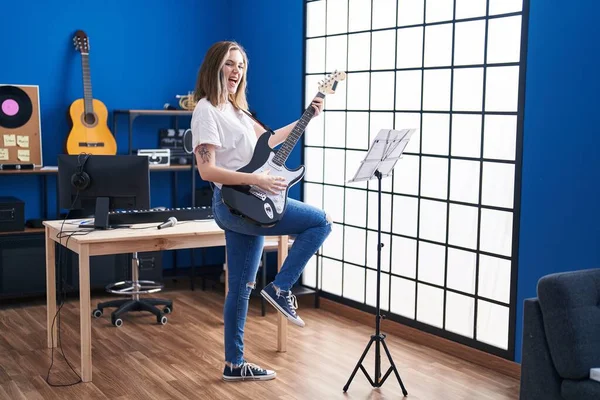 Young woman musician playing electrical guitar at music studio