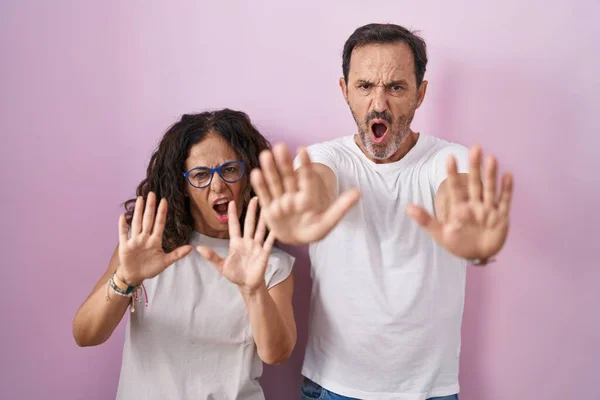 Middle Age Hispanic Couple Together Pink Background Doing Stop Gesture — Φωτογραφία Αρχείου