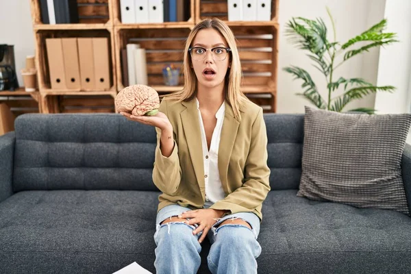 Young Blonde Woman Working Therapy Office Holding Brain Scared Amazed — Foto Stock