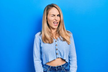 Gündelik giysiler giymiş genç beyaz kadın kameraya seksi bir ifadeyle bakıyor, neşeli ve mutlu bir yüzle.. 