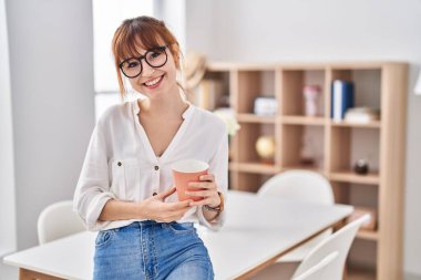 Evde kahve içen kendine güvenen genç bir kadın.