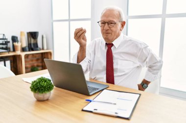 Senior man working at the office using computer laptop doing italian gesture with hand and fingers confident expression 