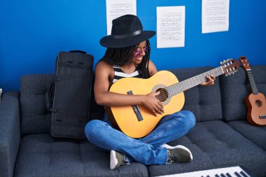 Müzik stüdyosunda klasik gitar çalan Afrikalı Amerikalı kadın müzisyen.