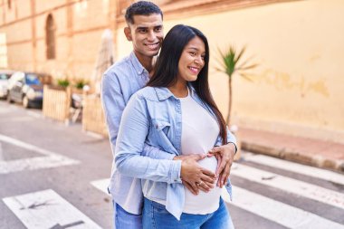 Latin bir çift bebek bekliyor. Sokakta birbirlerine sarılıyorlar.