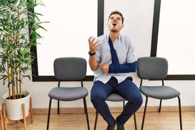 Yakışıklı genç adam, kolunda sakatlıkla bekleme odasında oturuyor. Deli gibi bağırıyor, bağırıyor, agresif ifadeler takınıyor ve kollarını kaldırıyor. hüsran kavramı. 