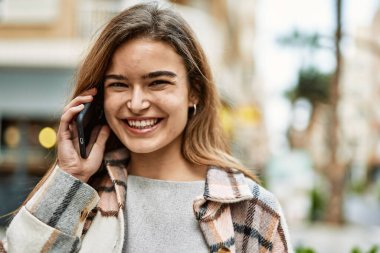 Sokakta akıllı telefondan konuşan genç sarışın kadın.